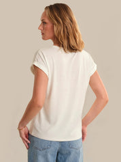 Woman wearing a plain white t-shirt and blue jeans against a neutral background