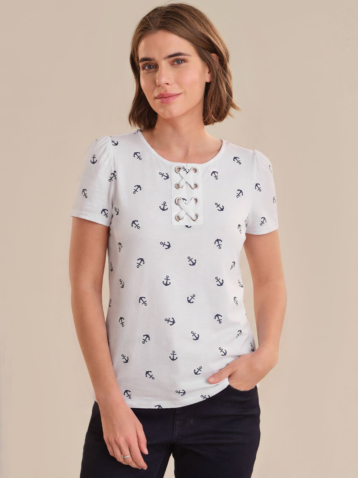 Woman wearing a white top with black anchor pattern against a beige background