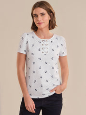 Woman wearing a white top with black anchor pattern against a beige background