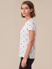 Woman wearing a white t-shirt with anchor pattern against a beige background