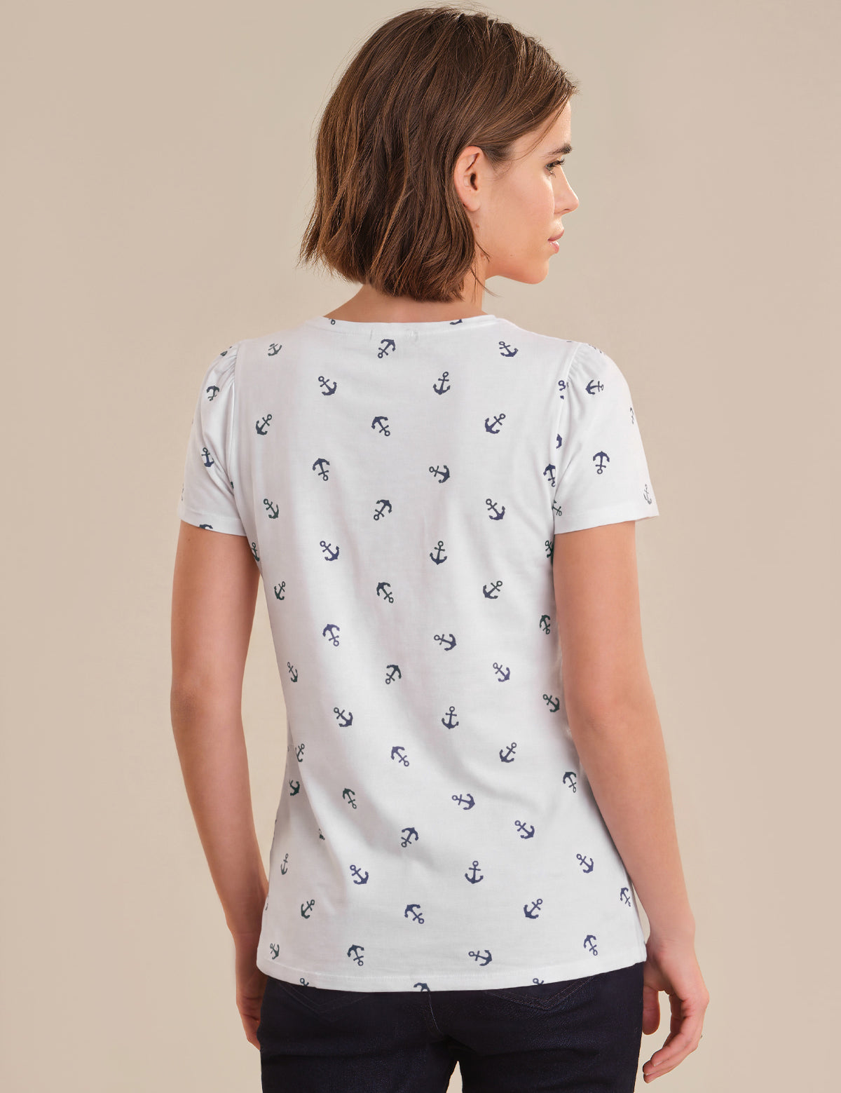 Woman wearing a white t-shirt with black anchor pattern on a beige background