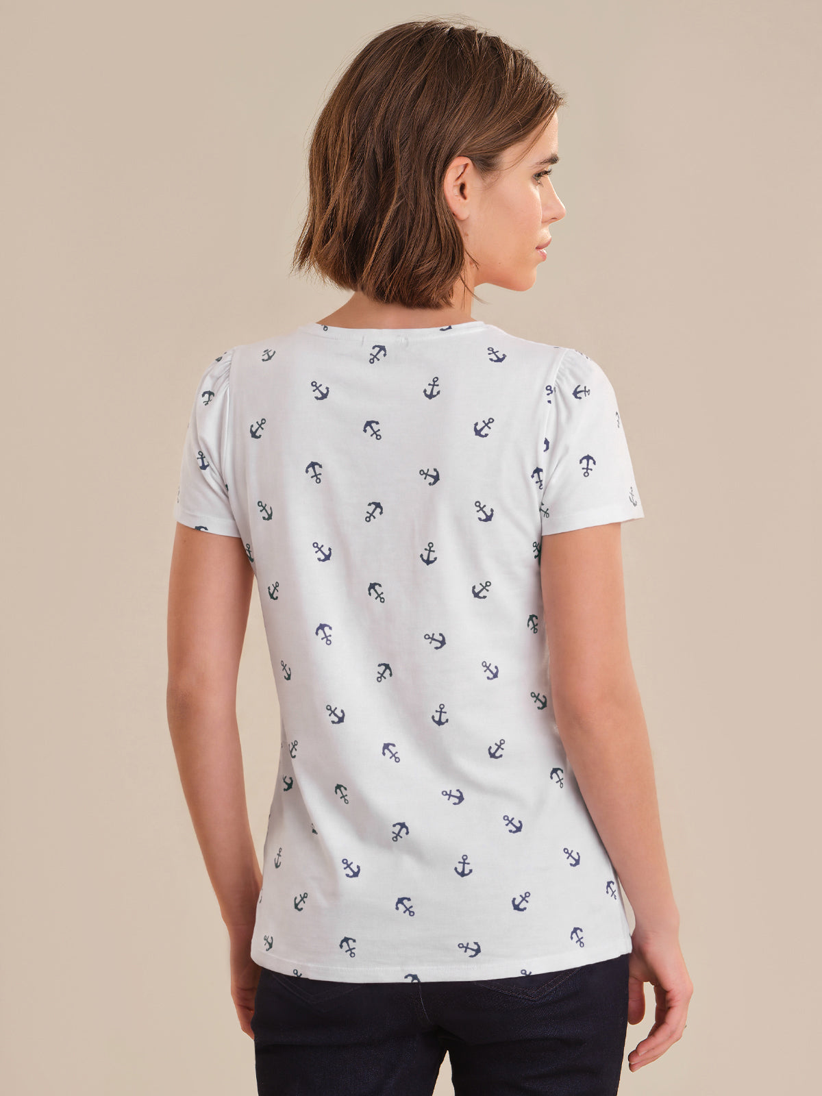 Woman wearing a white t-shirt with black anchor pattern on a beige background