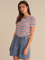 Woman wearing a striped shirt and denim shorts against a beige background