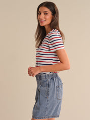 Woman wearing a striped shirt and denim shorts on a beige background