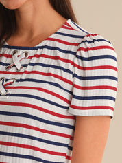 Close-up of a person wearing a red, white, and blue striped shirt with lace-up details.