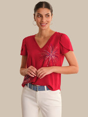 Woman wearing a red top with a decorative pattern on a beige background