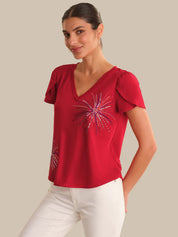 Woman wearing a red top with a decorative design on a beige background