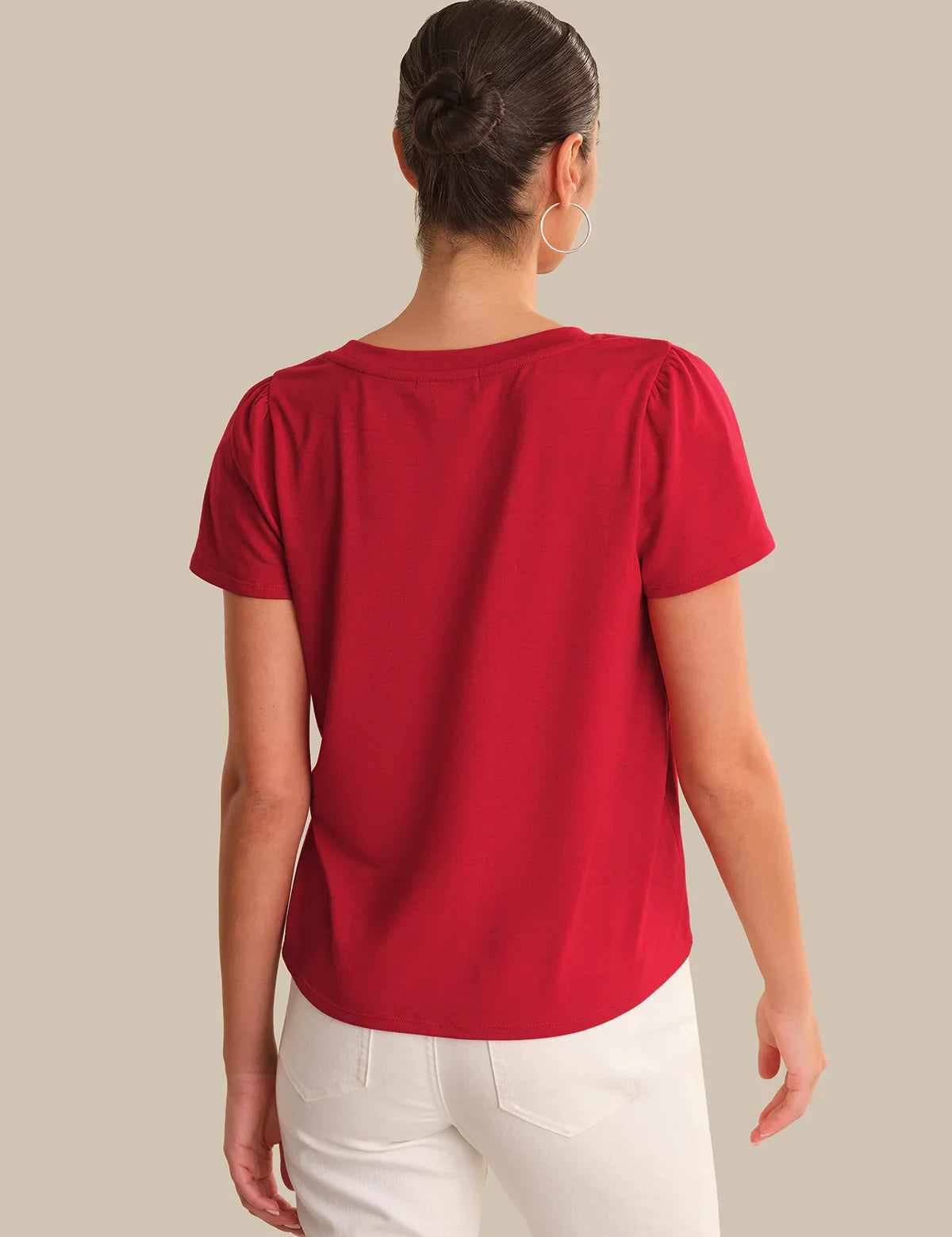 Person wearing a red top and white pants on a plain background