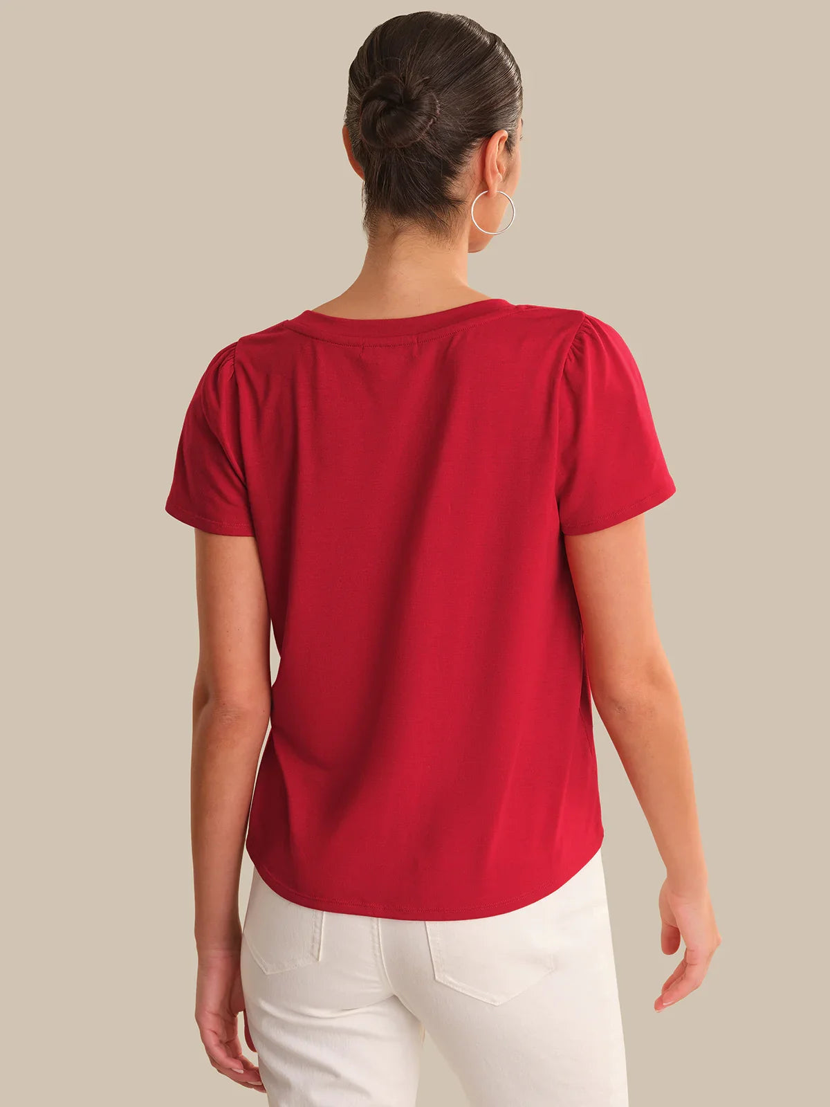 Person wearing a red top and white pants on a plain background