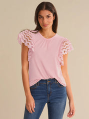 Woman wearing a pink blouse with lace sleeves on a beige background