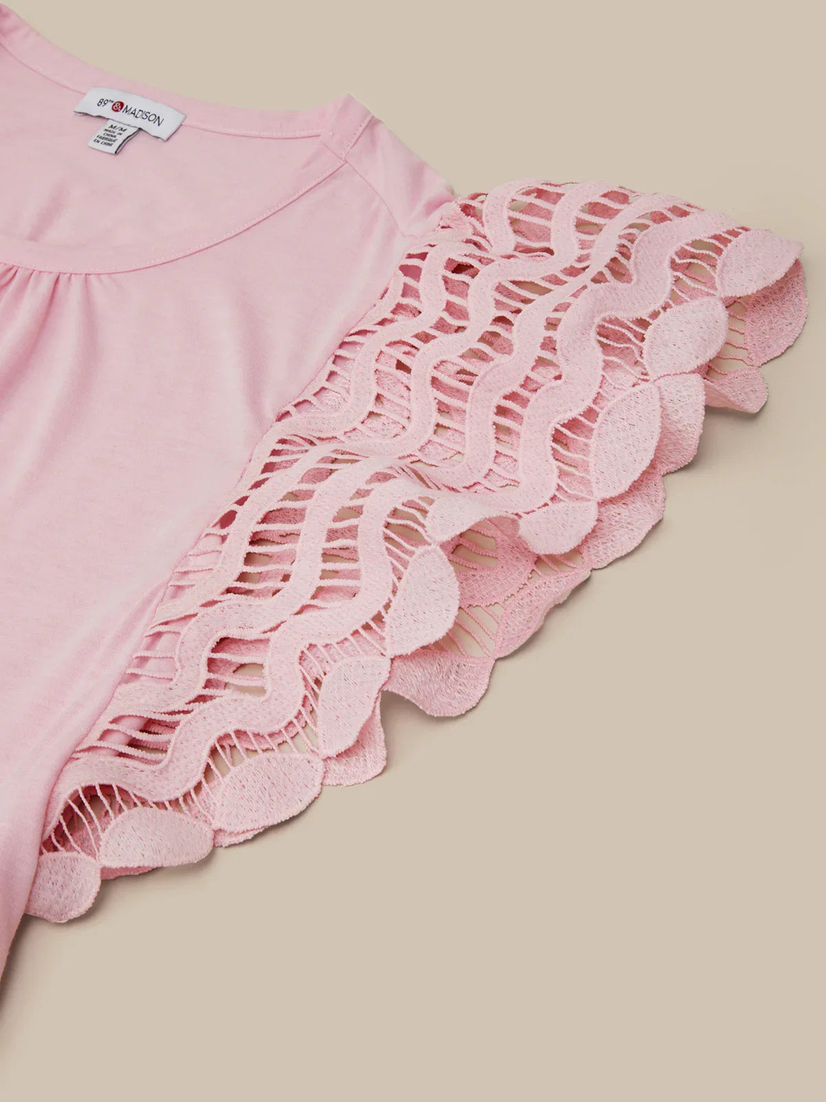 Pink top with lace detailing on a beige background