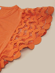 Orange top with intricate lace detailing on a beige background