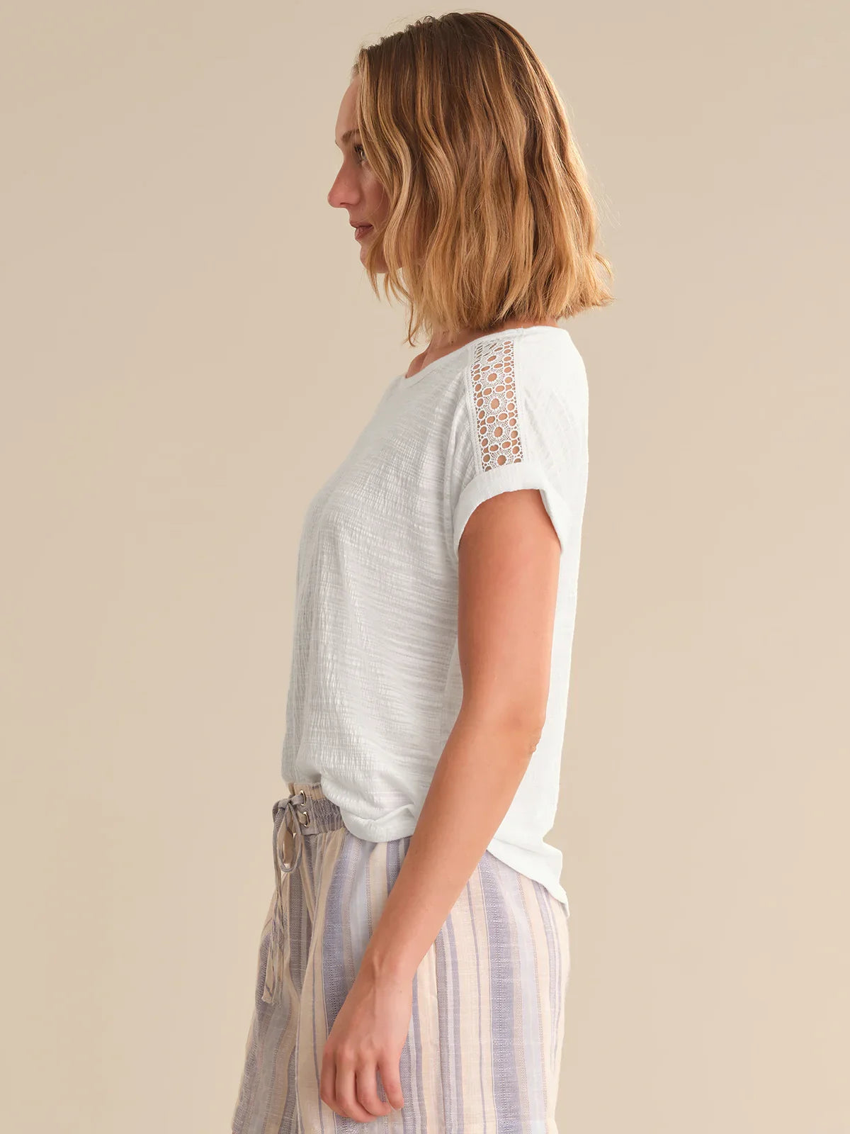 Woman wearing a light-colored top with lace details on a beige background