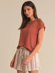 Woman wearing a rust-colored top and striped skirt on a beige background