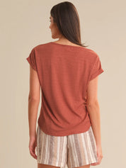 Woman wearing a rust-colored top and striped shorts on a beige background