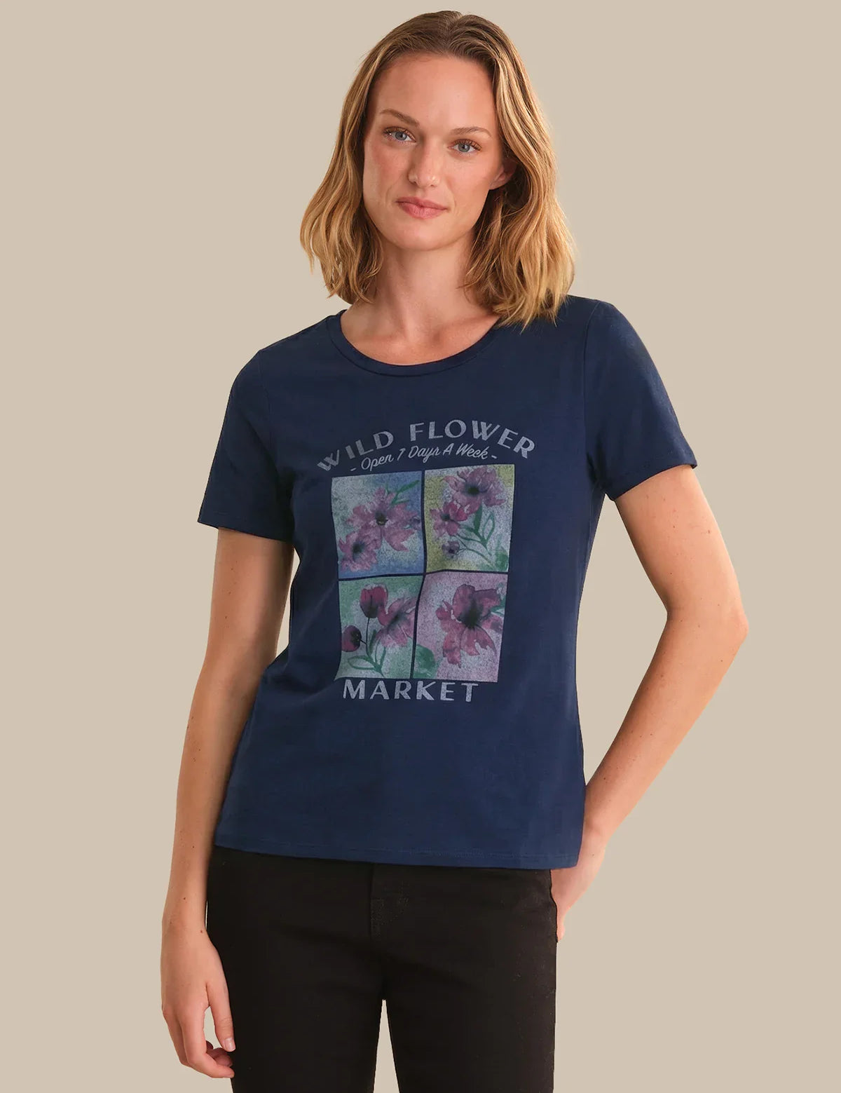 Woman wearing a navy blue t-shirt with floral design and text on a beige background