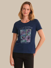 Woman wearing a navy blue t-shirt with floral design and text on a beige background