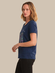 Woman wearing a blue t-shirt with a graphic design on a beige background