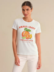 Woman wearing a white t-shirt with 'Amalfi Coast' and fruit graphic on a beige background