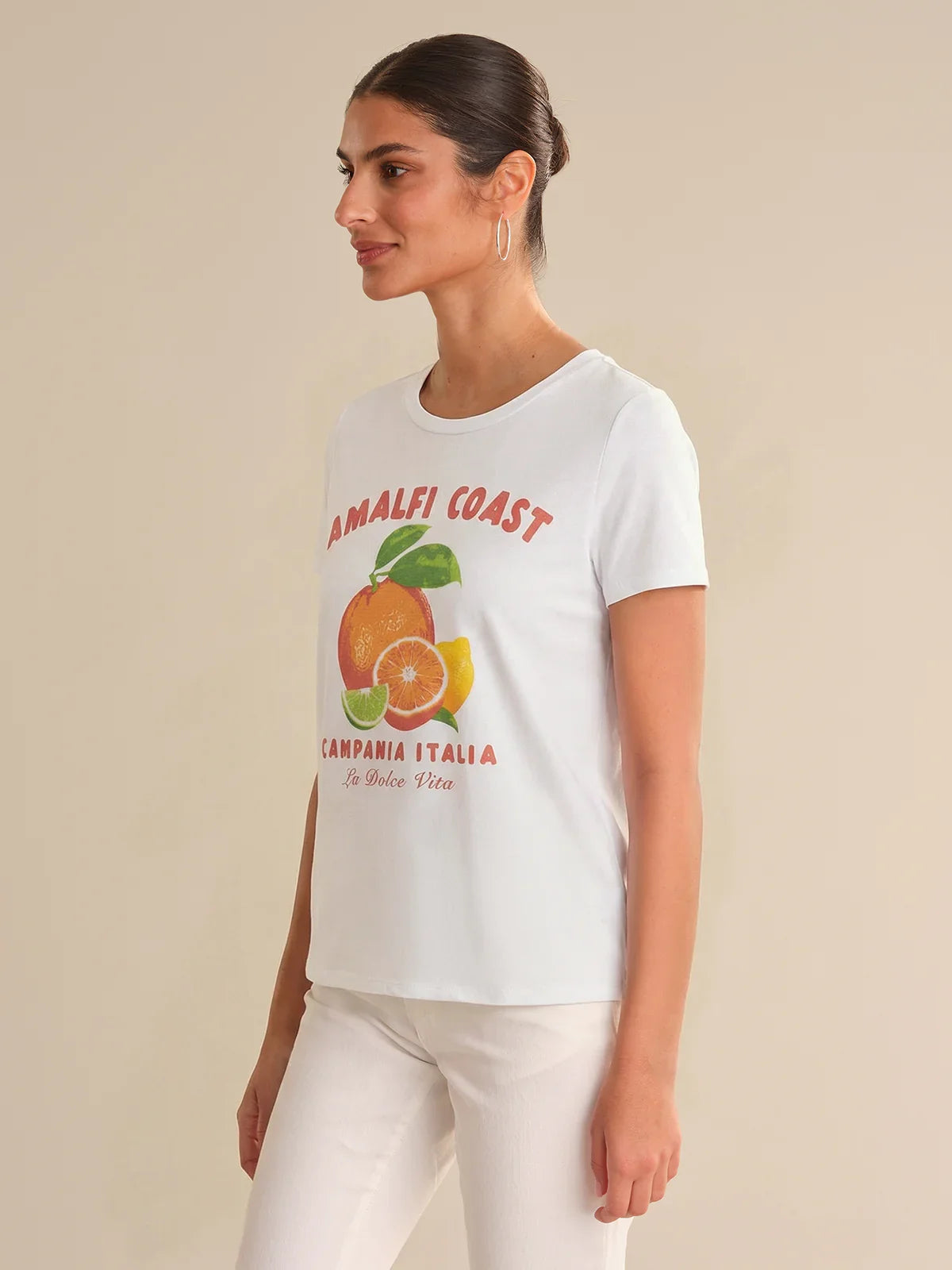Woman wearing a white t-shirt with 'Amalfi Coast' graphic design on a beige background