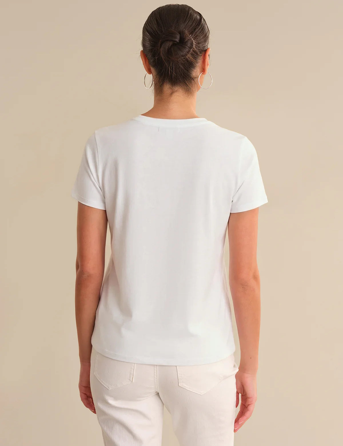 Person wearing a plain white t-shirt against a beige background