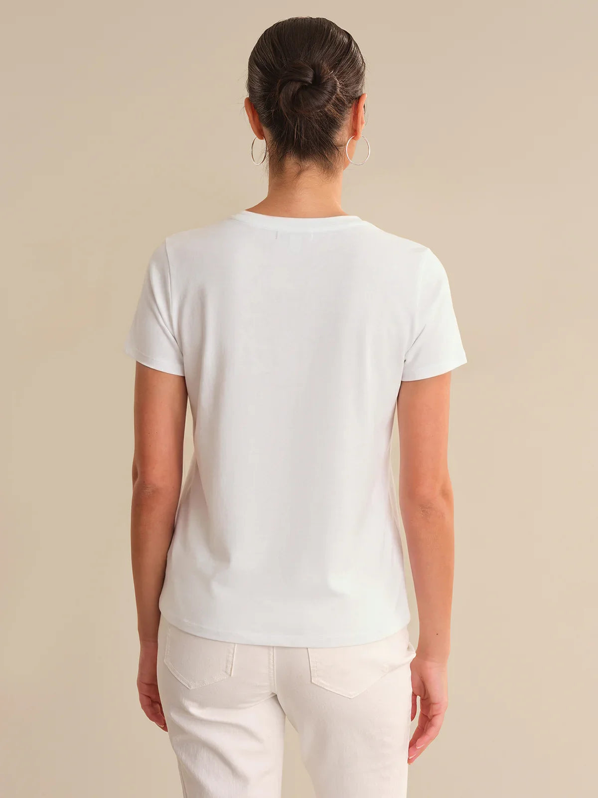 Person wearing a plain white t-shirt against a beige background