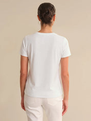 Person wearing a plain white t-shirt against a beige background