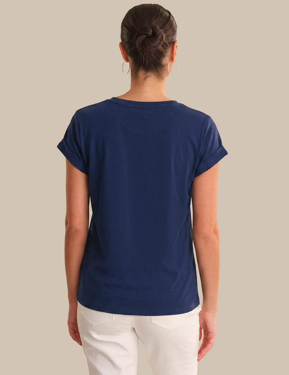Person wearing a blue t-shirt and white pants on a beige background