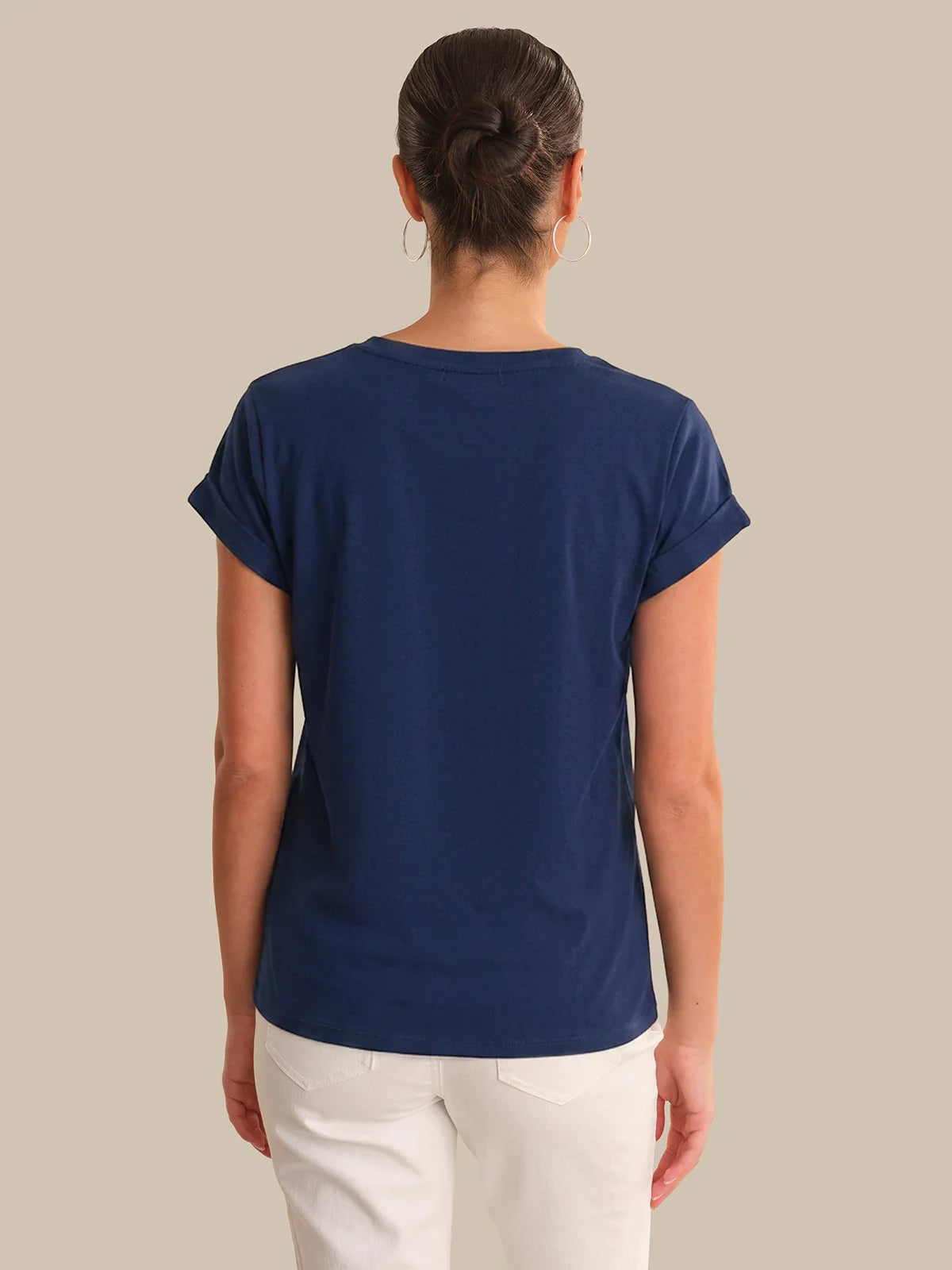 Person wearing a blue t-shirt and white pants on a beige background