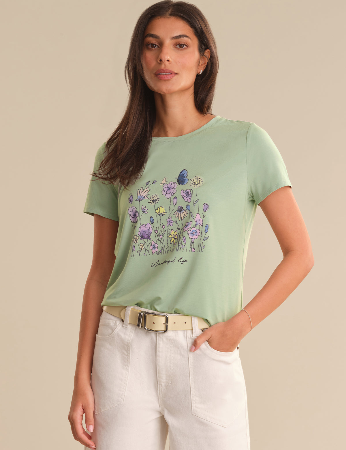 Woman wearing a light green t-shirt with a floral design on a beige background