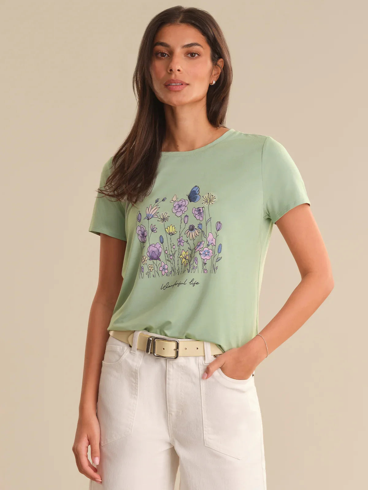 Woman wearing a light green t-shirt with a floral design on a beige background
