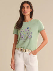 Woman wearing a light green t-shirt with a floral design on a beige background