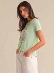 Woman wearing a light green t-shirt with a floral design on a beige background