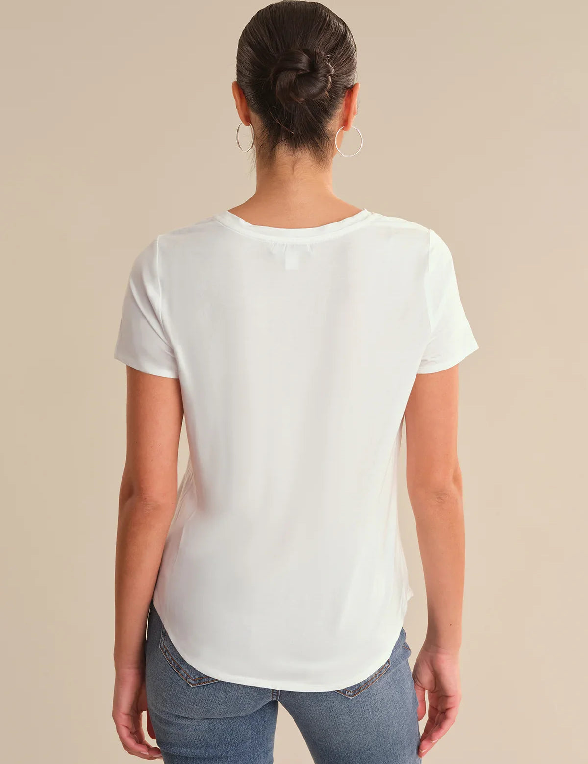 Person wearing a white t-shirt and blue jeans on a beige background