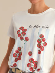 White t-shirt with red tomato design and 'la dolce vita' text on a beige background