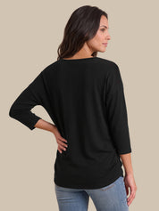 A woman shown from the back wearing a black three-quarter sleeve top and light blue jeans, standing against a solid beige background.