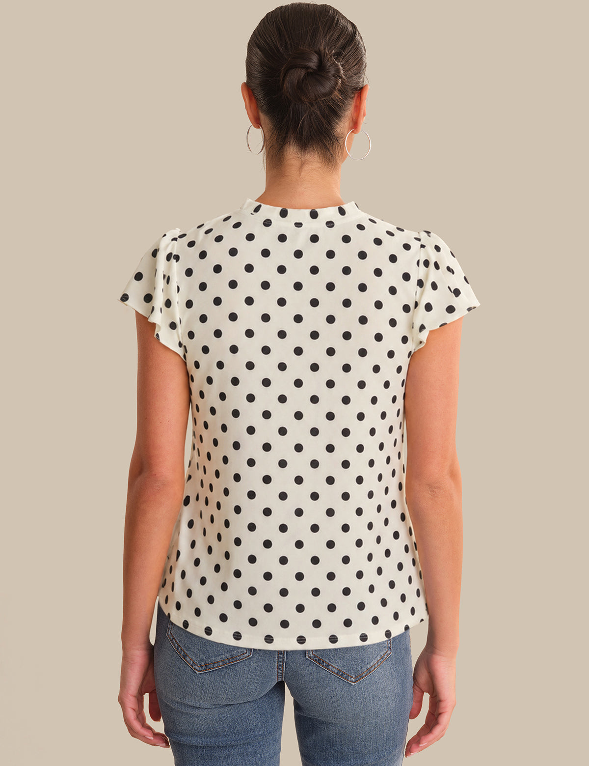 Person wearing a polka dot shirt and jeans on a beige background