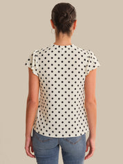 Person wearing a polka dot shirt and jeans on a beige background