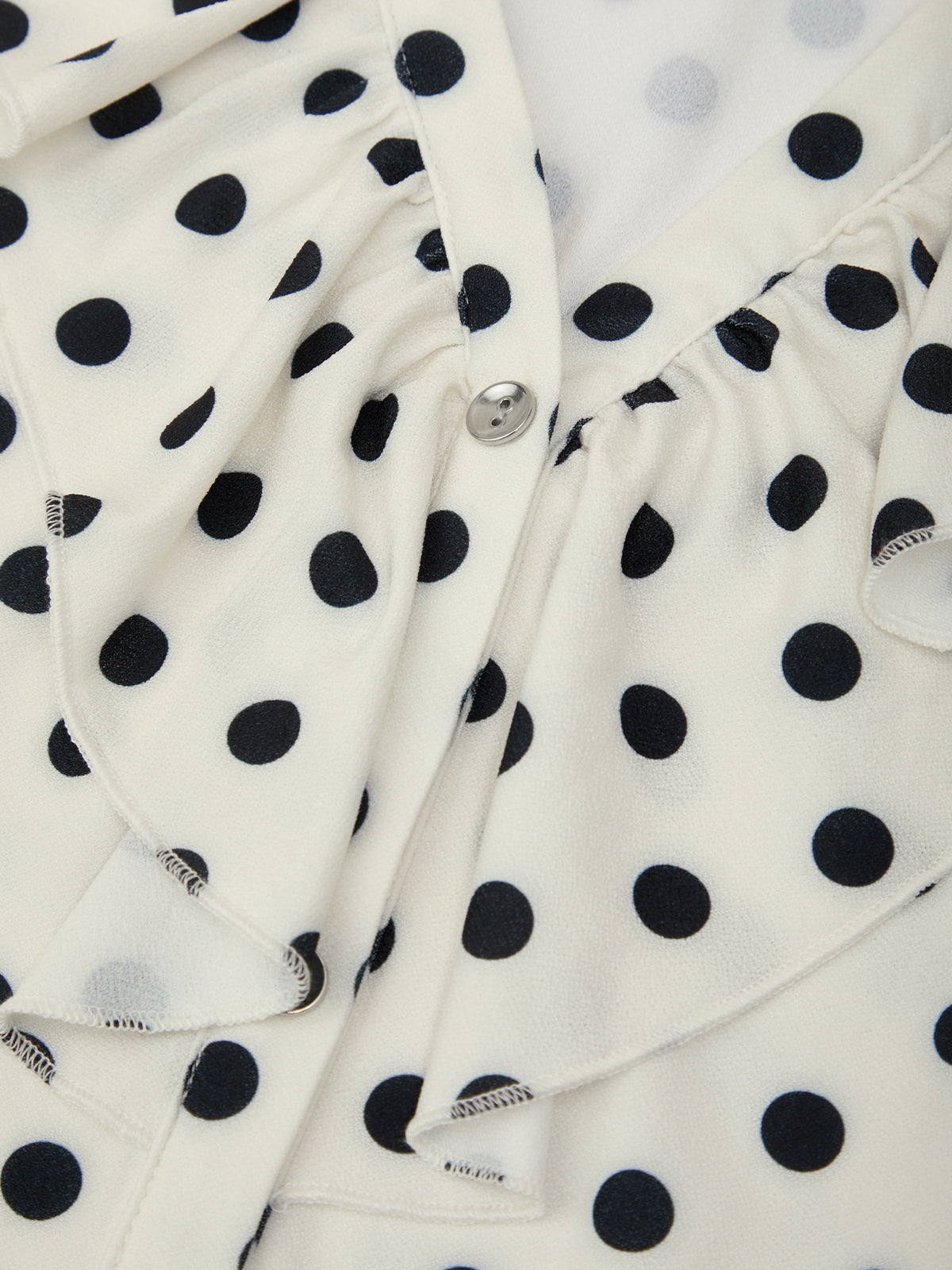 Close-up of a white fabric with black polka dots, featuring a brand label.