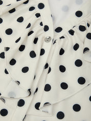 Close-up of a white fabric with black polka dots, featuring a brand label.