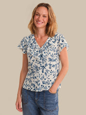Woman wearing a blue floral blouse and jeans on a beige background