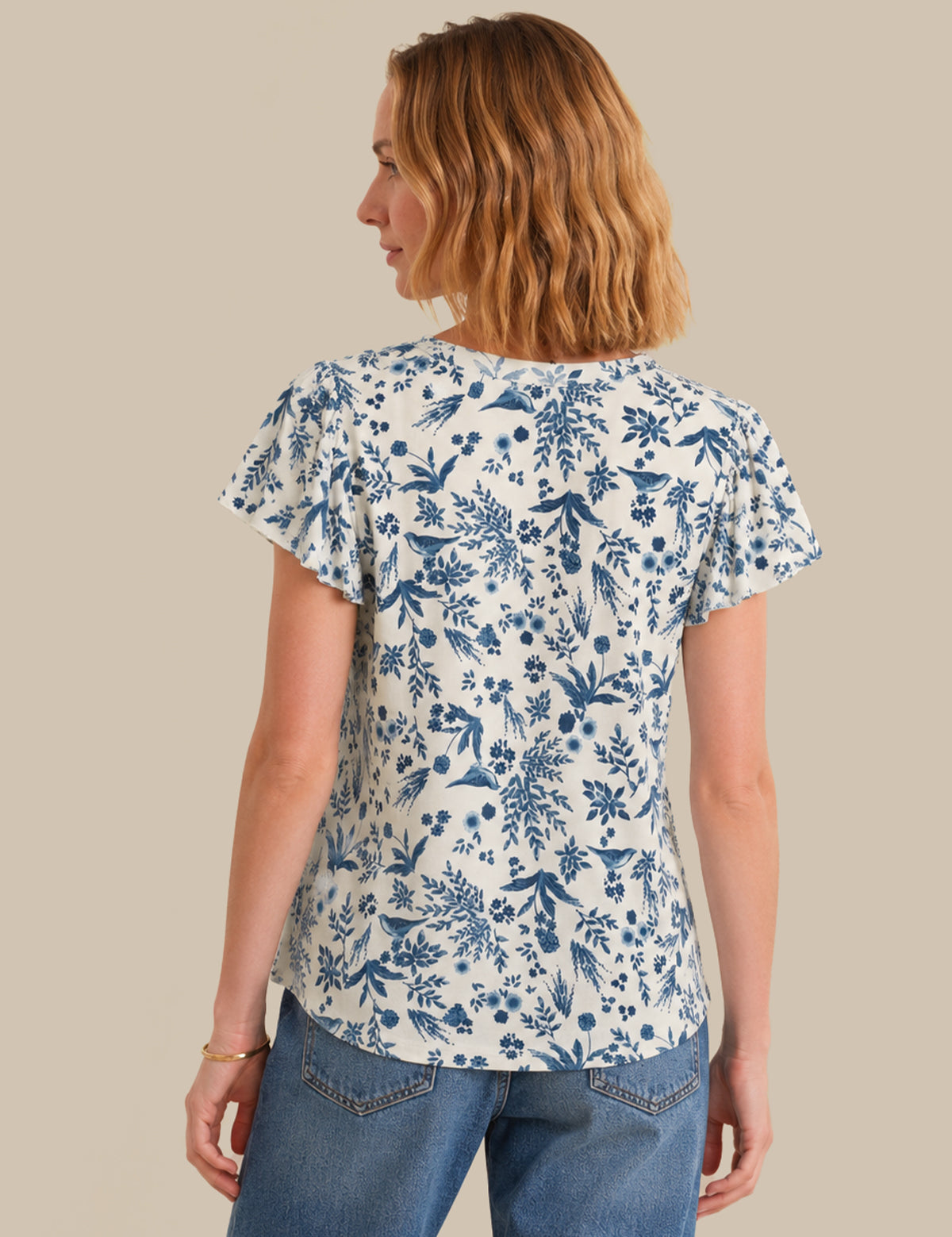 Woman wearing a blue floral patterned shirt against a beige background