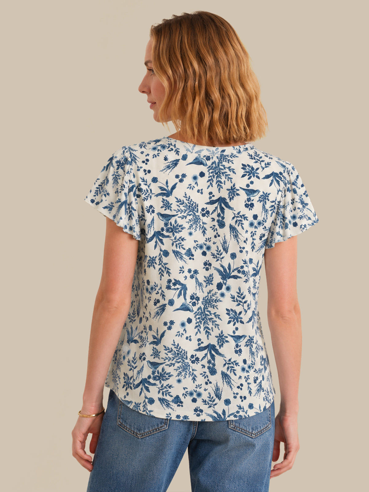 Woman wearing a blue floral patterned shirt against a beige background