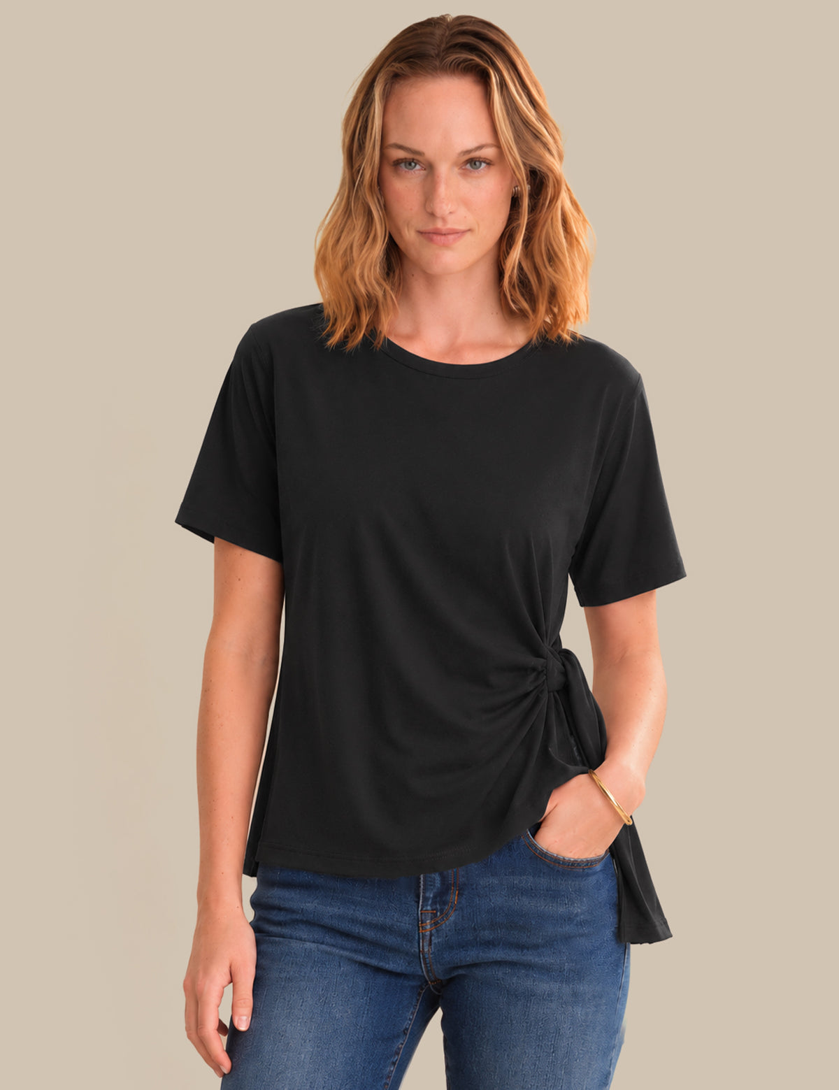 Woman wearing a black t-shirt with a knot detail on a beige background