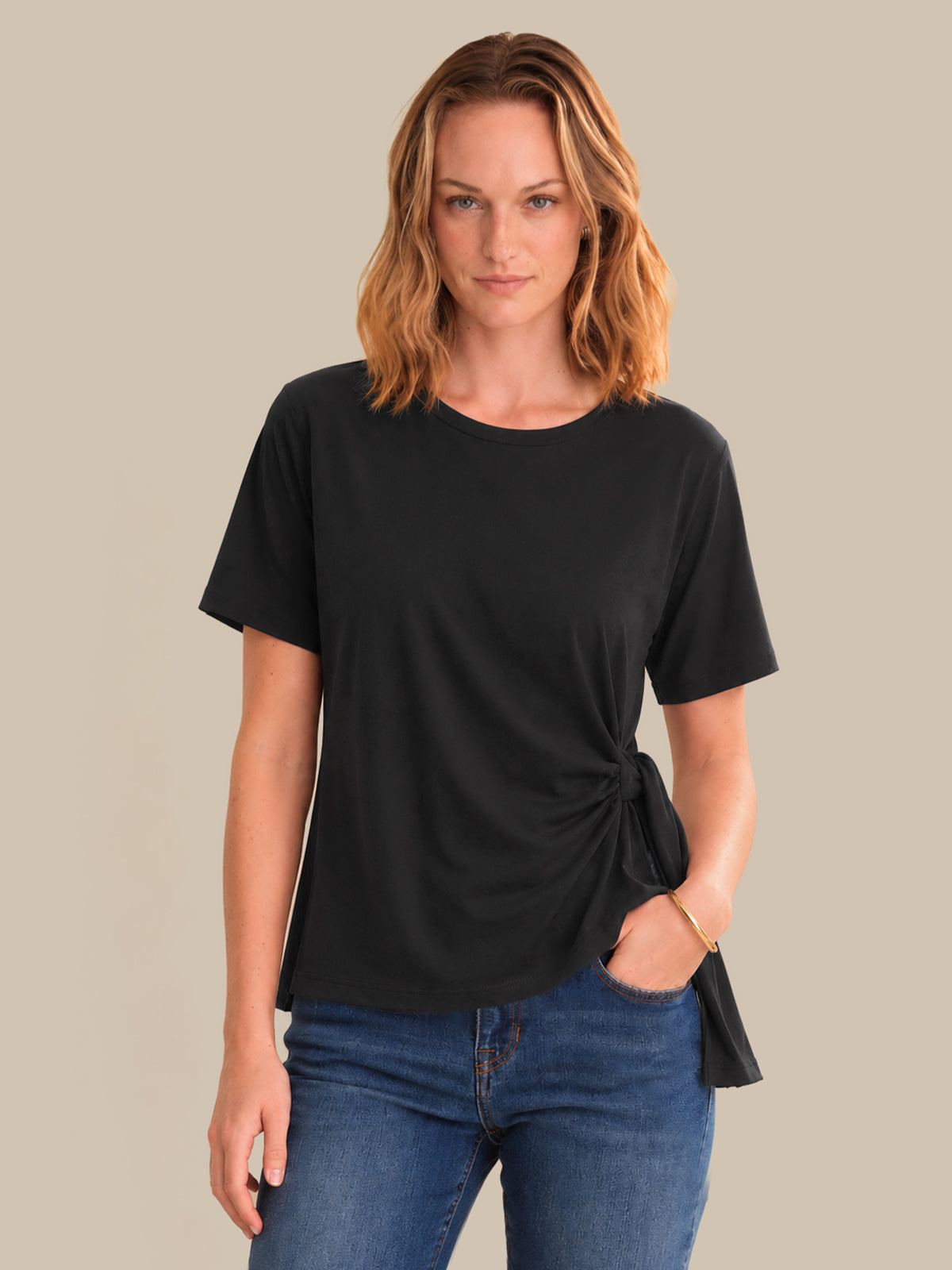 Woman wearing a black t-shirt with a knot detail on a beige background