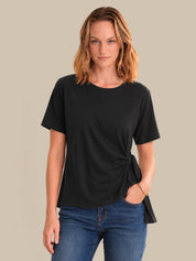 Woman wearing a black t-shirt with a knot detail on a beige background