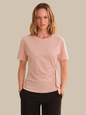 Woman wearing a pink t-shirt with a knot detail on a beige background