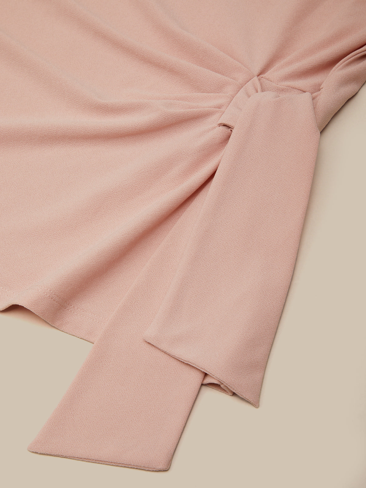 Pink fabric with a knot on a beige background