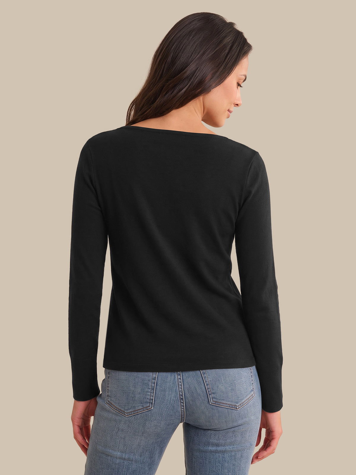 A woman shown from the back wearing a black long-sleeve boat-neck top and light blue jeans, set against a solid beige background.