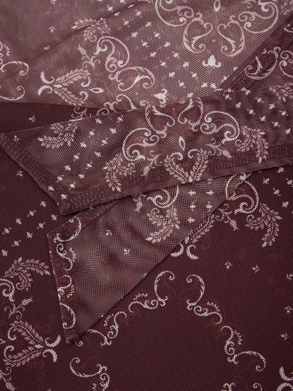 A close-up of a dark burgundy scarf with a white paisley and floral pattern, folded to show its texture and sheen.